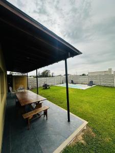 a picnic table and a bench under a black umbrella at Los Agapanthus in General Belgrano