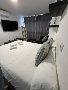 a bedroom with a large white bed and a television at Rooms Capulino in Málaga +8 photos