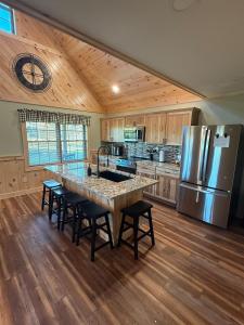 a kitchen with a large island with chairs and a refrigerator at Cattail Cabin in Waterville