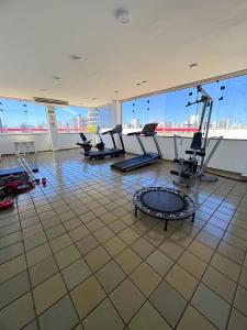 a gym with cardio equipment in a large room with windows at Flat central com estacionamento in Ribeirão Preto