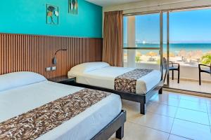 a hotel room with two beds and a view of the ocean at Hotel & Suites Domani in Progreso
