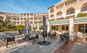 a hotel patio with tables and chairs and umbrellas at Résidence Pierre & Vacances Premium Les Calanques des Issambres in Les Issambres