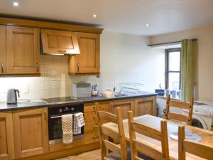 a kitchen with wooden cabinets and a table and chairs at Oaktree Cottage-Uk42227 in Low Borrowbridge