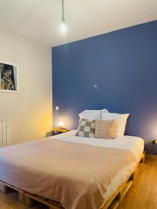 a bedroom with a large bed with a blue wall at Les oiseaux de la Slack in Ambleteuse