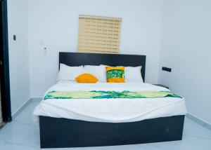a bed with orange and yellow pillows on it at Riverside Nest Owerri LTD in Owerri