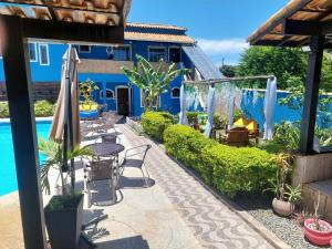 a patio with tables and chairs next to a pool at Pousada Summer Beach by Itaúna in Saquarema