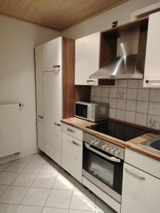 a kitchen with white cabinets and a microwave at Ferienwohnung Am Wald in Bad Marienberg