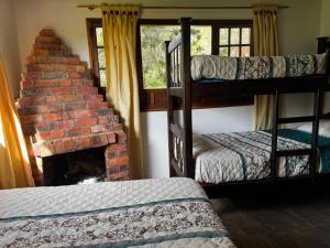 a room with bunk beds and a brick fireplace at Hotel Campestre los Duraznos in Cucunubá
