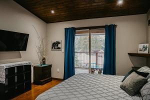 a bedroom with a bed and a window with blue curtains at Big Bear Chalet and spa in Revelstoke +60 photos