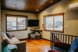 a living room with two windows and a flat screen tv at Big Bear Chalet and spa in Revelstoke