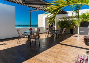a patio with tables and chairs and the ocean at Hotel & Suites Domani in Progreso