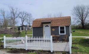 ein kleiner Schuppen mit einem weißen Zaun und einem Tisch in der Unterkunft AOK Campground & RV Park in Saint Joseph