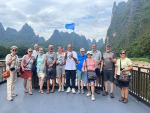 a group of people standing on a bridge with a blue flag at Guilin Qingshanshe Hotel -Free pick up train station stay two nights in Guilin +72 photos