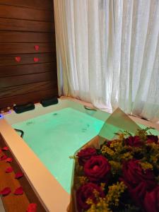 a bath tub filled with water with roses in it at Chales Vista da Mata 01 in Santa Teresa