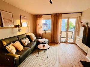 a living room with a leather couch and a table at CozyHome mit Netflix, voll ausgestatteter Küche, Zentrums- und Bahnhofsnah, Balkon, self-Check-in möglich in Bückeburg