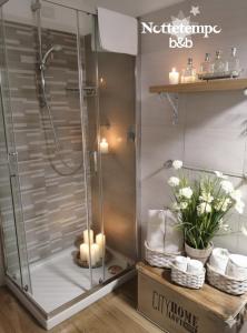 a shower stall in a bathroom with flowers and candles at B&B Nottetempo in Paupisi +41 photos