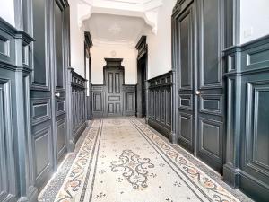 a hallway with black doors and a tile floor at Studio Villa Agathe in Troyes