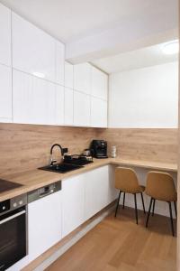 a kitchen with white cabinets and a sink and two chairs at Lana Apartmani Autor in Tuzla +4 photos