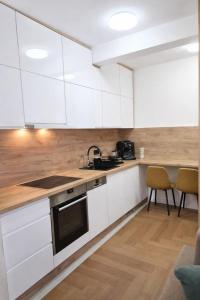 a kitchen with white cabinets and a table and chairs at Lana Apartmani Autor in Tuzla