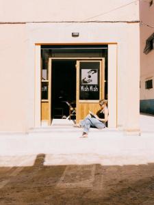 a woman sitting in front of a mexicanican store at Mish Mish in Tamraght Ouzdar