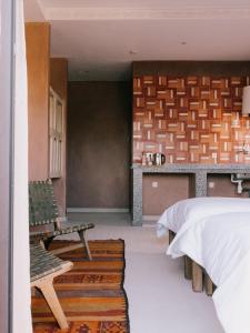 a bedroom with a bed and a table and benches at Mish Mish in Tamraght Ouzdar