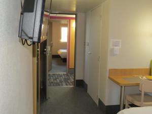 Zimmer mit einem TV und einem Zimmer mit einem Tisch. in der Unterkunft B&B HOTEL Yvetot in Yvetot