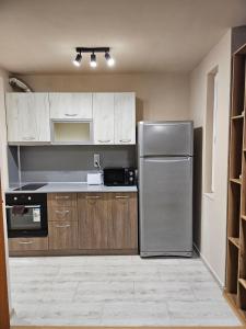 a kitchen with a stainless steel refrigerator and wooden cabinets at Дунав билдингс 3 in Pleven