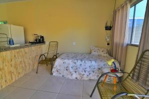 a bedroom with a bed and two chairs and a kitchen at Lolt Vila Boa Goiás in Goiás