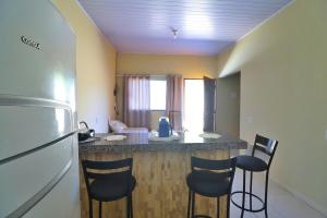 a kitchen with a counter with chairs and a refrigerator at Lolt Vila Boa Goiás in Goiás +15 photos