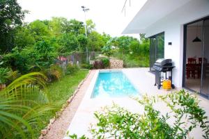 a swimming pool with a grill next to a house at Bustani Villa in Nyamanzi Kazole +13 photos