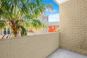 a balcony with a brick wall and a palm tree at The Modern Retreat in Sydney