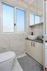 a bathroom with a toilet and a sink and two windows at The Modern Retreat in Sydney +4 photos