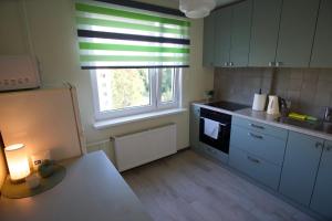 a kitchen with white cabinets and a sink and a window at Apartments in Kauguri in Jūrmala
