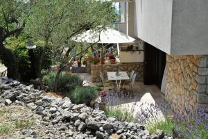 a patio with a table and an umbrella and flowers at Apartments Marija in Cres