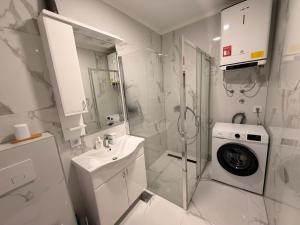 a white bathroom with a sink and a washing machine at Apartman TERRASSE in Trebinje +11 photos