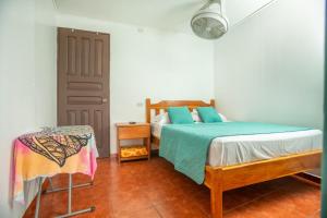 a bedroom with a bed and a table and a fan at Hostal Nuevo Arenal downtown, private rooms with bathroom in Nuevo Arenal