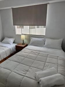 a bedroom with two beds with white sheets at Miraflores View in Lima