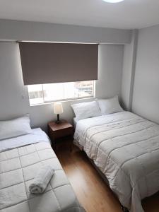 two beds in a small bedroom with a window at Miraflores View in Lima +12 photos