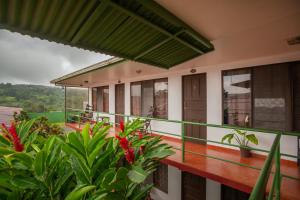 a balcony of a house with red flowers at Hostal Nuevo Arenal downtown, private rooms with bathroom in Nuevo Arenal