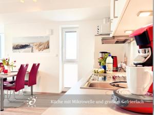a kitchen with a sink and a table with chairs at Penthouse de Ool Blick auf das Wattenmeer in Neufeld