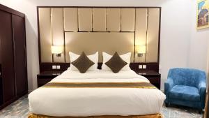 a bedroom with a large bed and a blue chair at فندق ذكرى in Taif