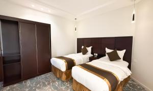 two beds in a hotel room with white walls at فندق ذكرى in Taif