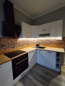 a kitchen with white cabinets and a stove top oven at Apartament Centrum in Płock +4 photos