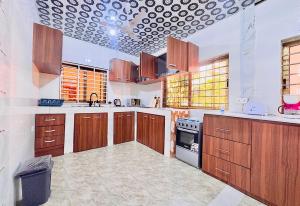 a large kitchen with wooden cabinets and a ceiling at Villa de chez nous in North Legon
