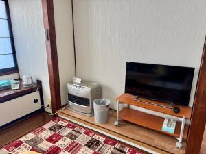 a living room with a flat screen tv and a table at ANFT-shiro in Azumino