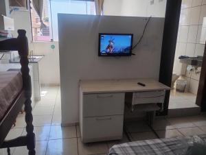 a room with a desk with a television on a wall at kitnet08 para 04 pessoas bem localizada garagem in Ourinhos