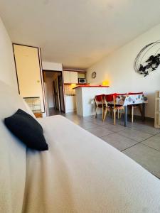 a bedroom with a bed and a kitchen with a table at Les Soleillades-T2 pour 5 pers-piscine, parking privé- LaConciergerieByNina in Palavas-les-Flots