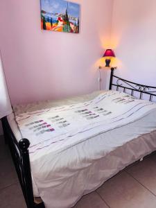 a bed with a white comforter on top of it at Les Soleillades-T2 pour 5 pers-piscine, parking privé- LaConciergerieByNina in Palavas-les-Flots