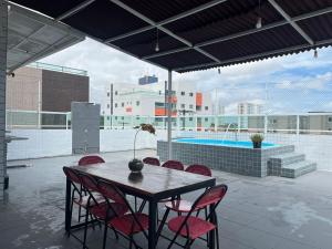 a table and chairs on a patio with a pool at Vista Real - cobertura com 160m2 - Piscina privada in João Pessoa