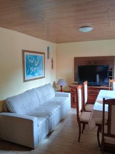 a living room with a couch and a flat screen tv at Hospedagem do Rio in Nova Friburgo